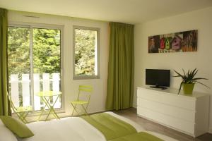 1 dormitorio con 1 cama, TV y ventana en Latitude Ouest Hotel Restaurant & Spa, en Locronan