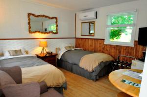 - une chambre avec 2 lits, une table et un miroir dans l'établissement Motel des Deux Lacs, à Waterloo