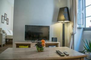 Melita corner apartment في فاليتا: غرفة معيشة فيها تلفزيون وطاولة عليها مزهرية