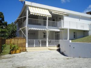 een wit huis met een veranda en een balkon bij Kouleur Karayib in Le Gosier