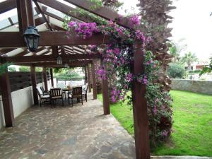 a pergola with purple flowers and a table and chairs at Villa Galleria in Perivolia
