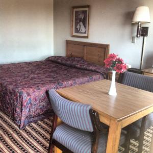 une chambre d'hôtel avec un lit et une table avec un vase de fleurs dans l'établissement Relax Inn - Shelby, à Shelby