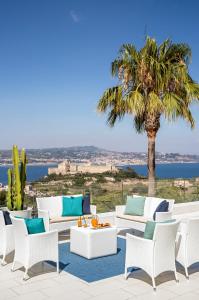 a patio with white chairs and a palm tree at Villa Gervasio in Bacoli