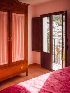 a bedroom with a bed and an open door to a balcony at El Buen Sitio in Zahara de la Sierra
