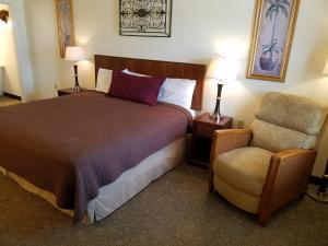 a hotel room with a bed and a chair at West Plains Motel in West Plains
