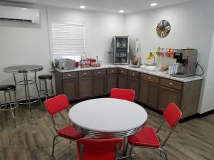 een keuken met een witte tafel en rode stoelen bij West Plains Motel in West Plains