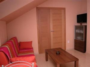 uma sala de estar com um sofá vermelho e uma mesa em Capricho de Bascuas em Bascuas