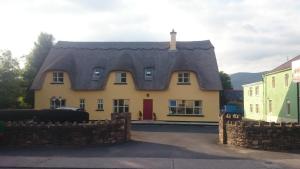a yellow house with a gray roof at Inspiration Lodge in Anascaul