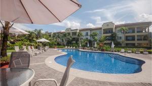 a pool at a hotel with chairs and an umbrella at Ocean View Condo in Los Sueños in Herradura