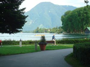 a man sitting on a bench next to a lake at Gästehaus Meran in Bad Wiessee