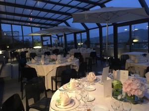 un restaurant avec des tables blanches, des chaises et des parasols dans l'établissement Grande Albergo Potenza, à Potenza