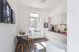 eine Küche mit weißen Schränken und einem Tisch und Stühlen in der Unterkunft Family-Apartments Freiburg in Freiburg im Breisgau
