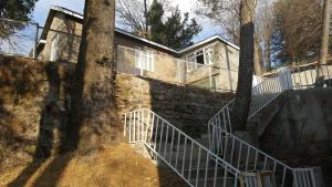 a house with a staircase in front of a tree at Pine Top Hotel Murree in Murree +34 photos
