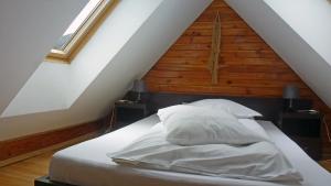 ein Bett mit weißer Bettwäsche und Kissen im Dachgeschoss in der Unterkunft Sura Pietrei Craiului in Zărneşti
