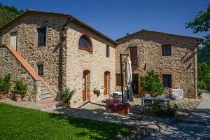 a stone house with a garden and a patio at Agriturismo La Marginella in Pescia
