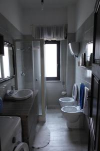 ein Bad mit 2 Waschbecken, einem WC und einem Fenster in der Unterkunft Appartamento Confortevole I 3 cocos in Maierato