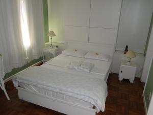 1 cama blanca en una habitación pequeña con 2 lámparas en Casa Temporada Itaipava, en Petrópolis