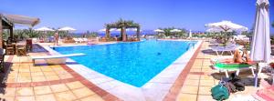 a swimming pool with people sitting on chairs and umbrellas at Panselinos Hotel in Mithymna