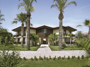 una casa con palmeras delante en TUI BLUE Palm Garden en Kizilagac