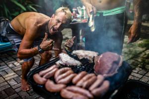 un hombre está cocinando carne en una parrilla en Tamarindo Backpackers, en Tamarindo