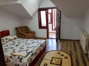 a bedroom with a bed and a chair and a window at Casa DeLux in Băile Olăneşti