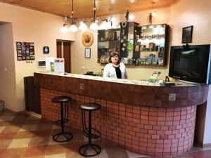 a woman standing behind a bar in a restaurant at Agio Hotel in Kolochava