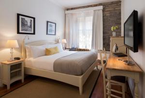 Dormitorio con cama, escritorio y TV en Auberge Saint-Pierre, en Quebec