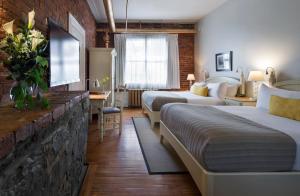 a hotel room with two beds and a tv at Auberge Saint-Pierre in Quebec City +18 photos