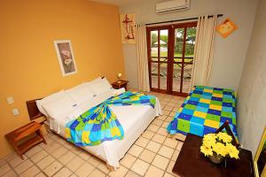 a bedroom with a bed and a door to a patio at Igarakuê Hotel Pousada in Japaratinga