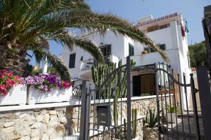een wit huis met een palmboom en bloemen bij Casa Baia Luna in Ponza