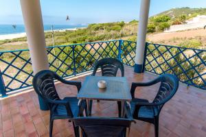 een tafel en stoelen op een balkon met uitzicht op het strand bij Quarto Crescente in Nazaré