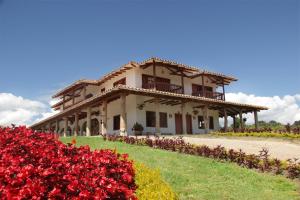 una casa grande con flores rojas delante de ella en Hotel Estorake San Agustin Huila, en San Agustín