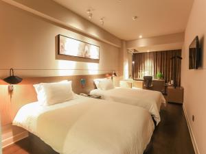 海口市にあるJinjiang Inn Haikou Guomao Jinlong Roadのベッド2台とデスクが備わるホテルルームです。