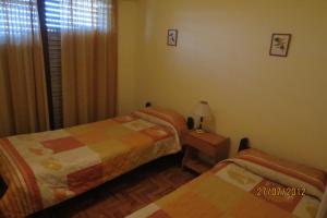 a bedroom with two beds and a table with a lamp at Hotel Carilo in Mar del Plata