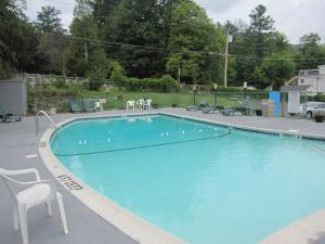 a large blue swimming pool with chairs and tables at Howard Johnson by Wyndham Lake George in Lake George