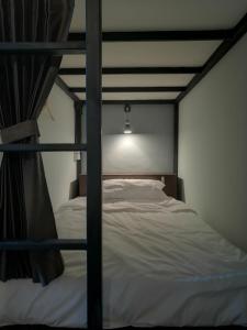 バンコクにあるバックパック　ステーションのベッドルーム1室(白いシーツが備わる二段ベッド1組付)
