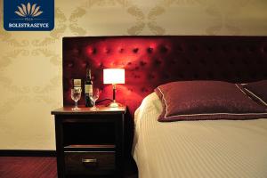 1 cama con cabecero rojo y mesa con copas de vino en Hotel Villa Bolestraszyce, en Przemyśl