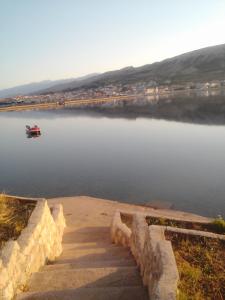 un pequeño barco en un lago con un barco en el agua en Apartments Boki, en Pag