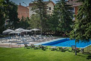 a pool with chairs and umbrellas in a grassy area at Hotel Gran Sol in Solsona