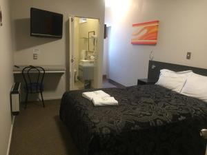 Una habitación de hotel con una cama con dos toallas. en Motel on Carroll, en Dunedin