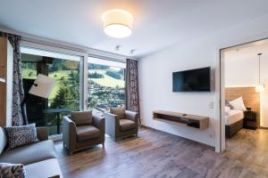 salon z kanapą, krzesłami i telewizorem w obiekcie Adler Resort w Saalbach Hinterglemm