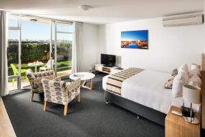 
a room with a bed, desk, chair and a television at Be. Fremantle in Fremantle
