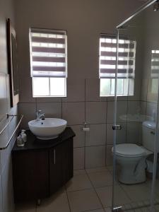 a bathroom with a sink and a toilet and windows at JS Inn in Nelspruit