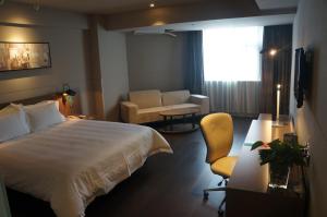 海口市にあるJinjiang Inn Haikou Guomao Jinlong Roadの大きなベッドと椅子のあるホテルの部屋