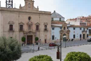 un gran edificio de piedra con un coche aparcado delante de él en Apartamentos San Agustín, en Murcia