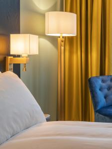 a bedroom with two lamps and a blue chair at Thon Hotel Lofoten in Svolvær