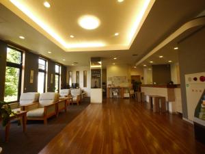 an empty waiting room with white chairs and wood floors at Hotel Route-Inn Nakatsugawa Inter in Nakatsugawa
