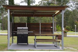 a picnic shelter with a grill and a picnic table at Fairway Lodge Motel in Kempsey