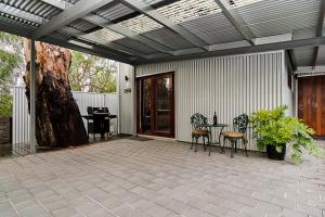 een patio met een tafel en stoelen en een boom bij Eagle Foundry Bed & Breakfast in Gawler