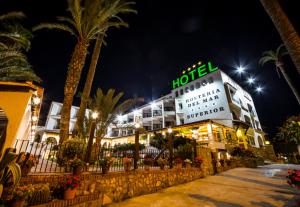 a hotel at night with palm trees in front of it at Hostería del Mar in Peniscola